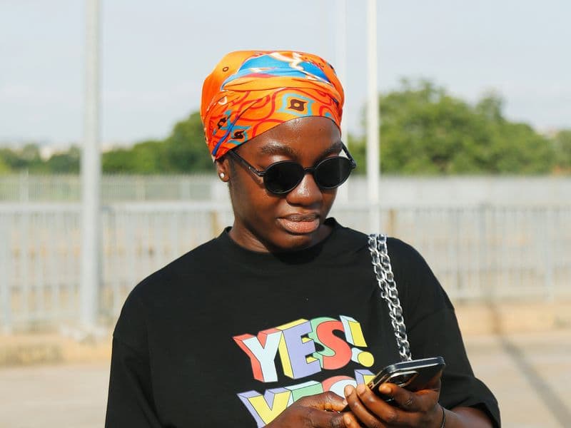 Woman using an app on her phone on a street in Abuja