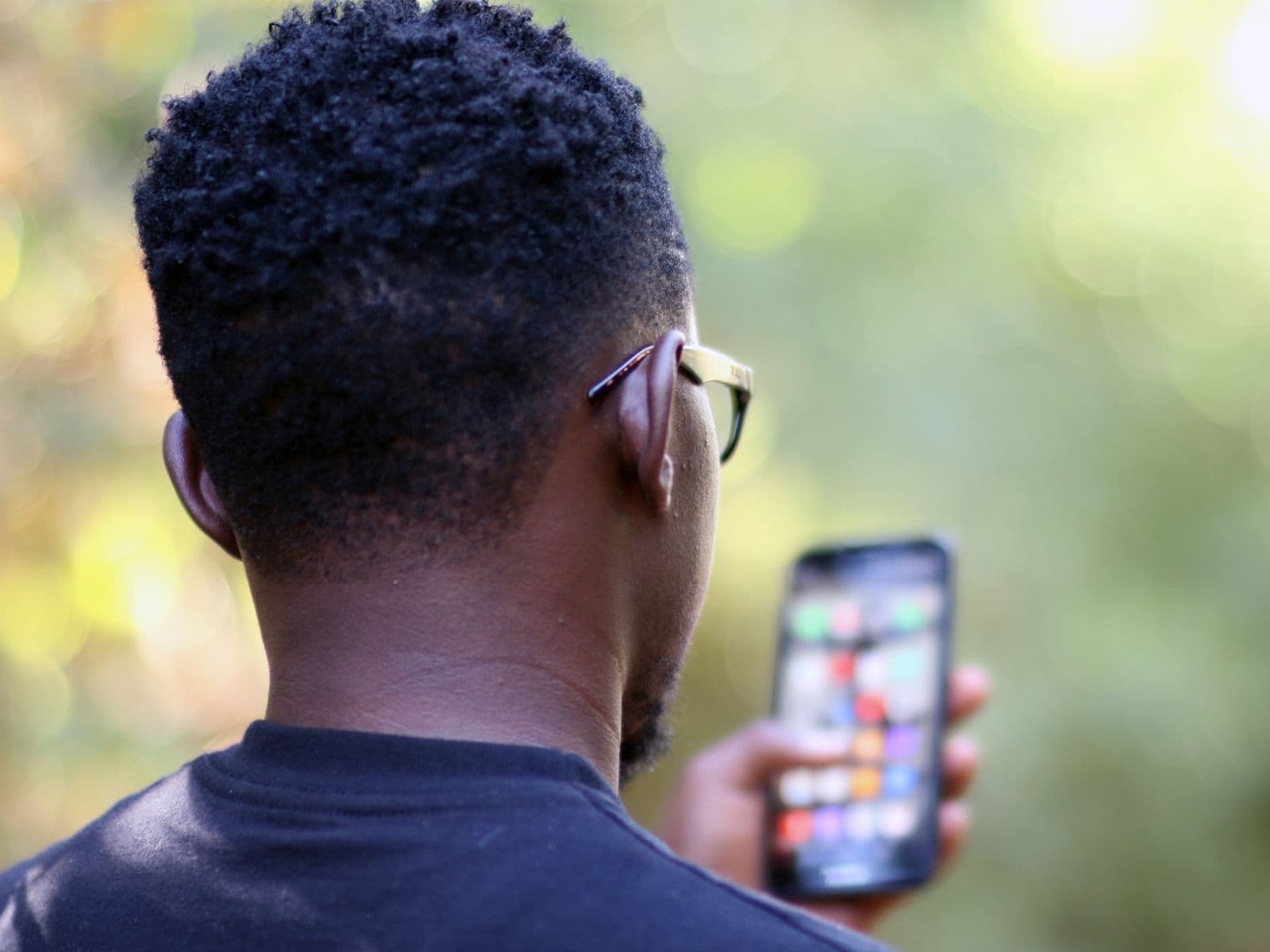 A man outdoors in Kenya checking his phone, mobile money on the go